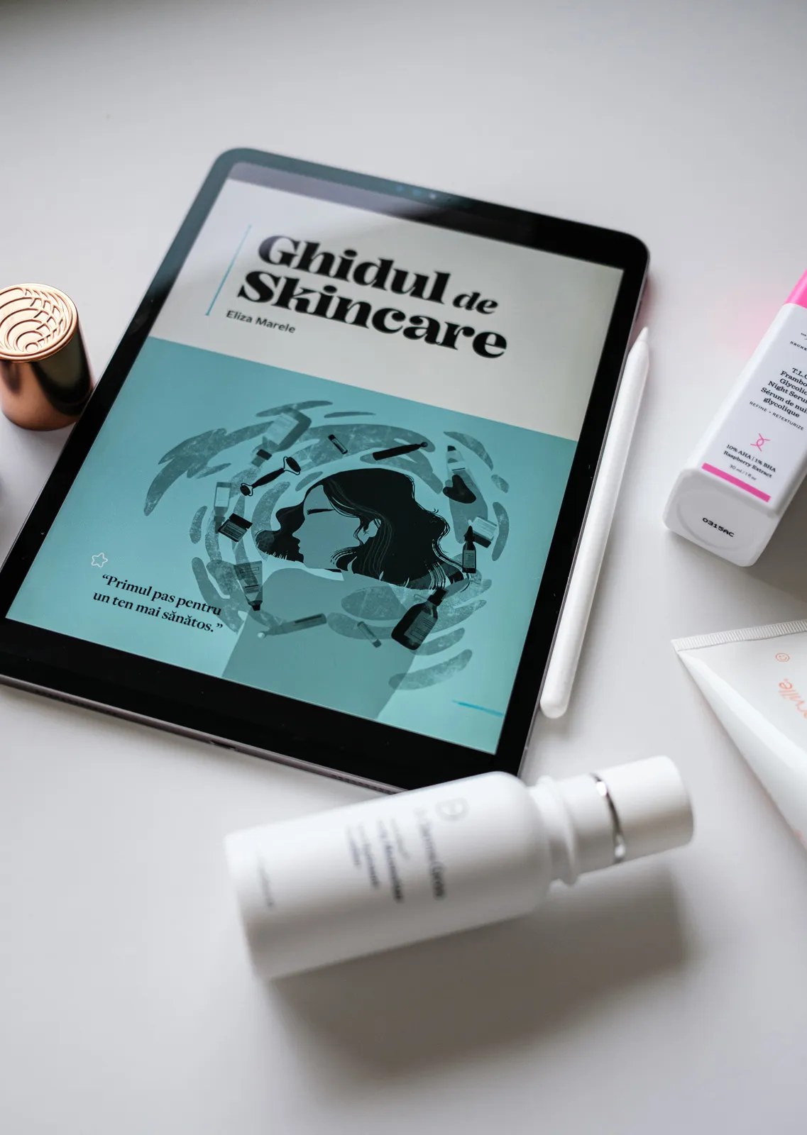 Poza cu ghidul de skincare pe un iPad inconjurat de produse pentru ten